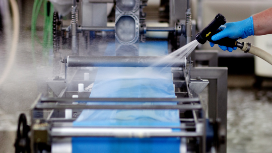Food safety technician swabbing conveyor belt
