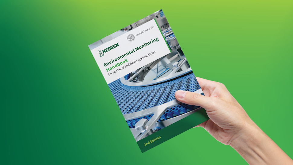 Hand holding the second edition of the Neogen Environmental Monitoring Handbook.